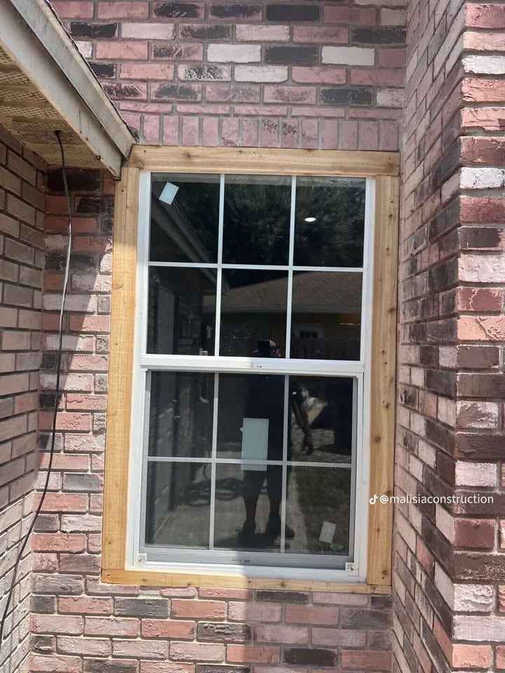 New double-hung window with white frame and twelve panes installed in red brick wall