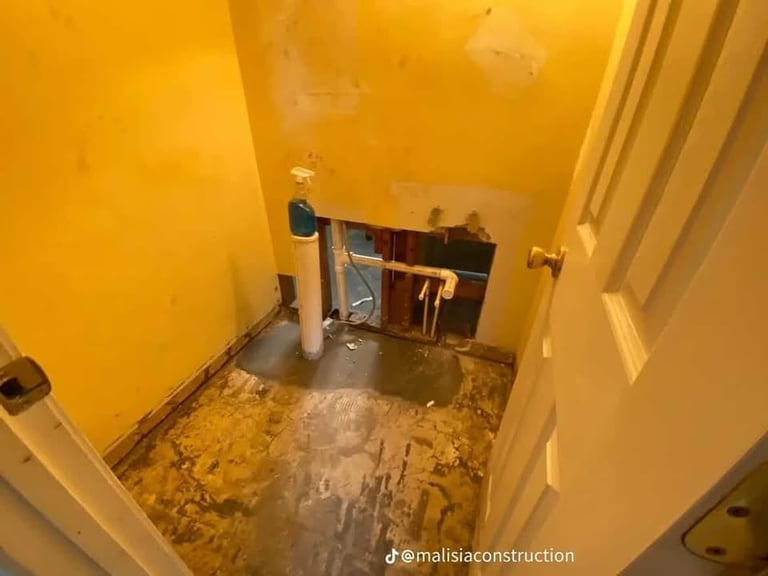 A bathroom under construction with bright yellow walls, exposed subflooring, and wooden shelving units during renovation