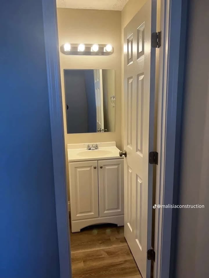 Modern bathroom with white vanity cabinet, mirror with LED lights, and blue-painted walls