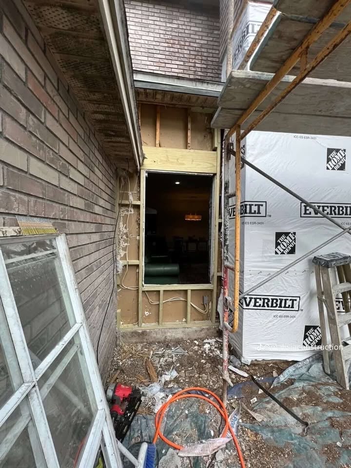Narrow alleyway entrance to a building under renovation with brick walls, construction materials, and debris scattered on the ground